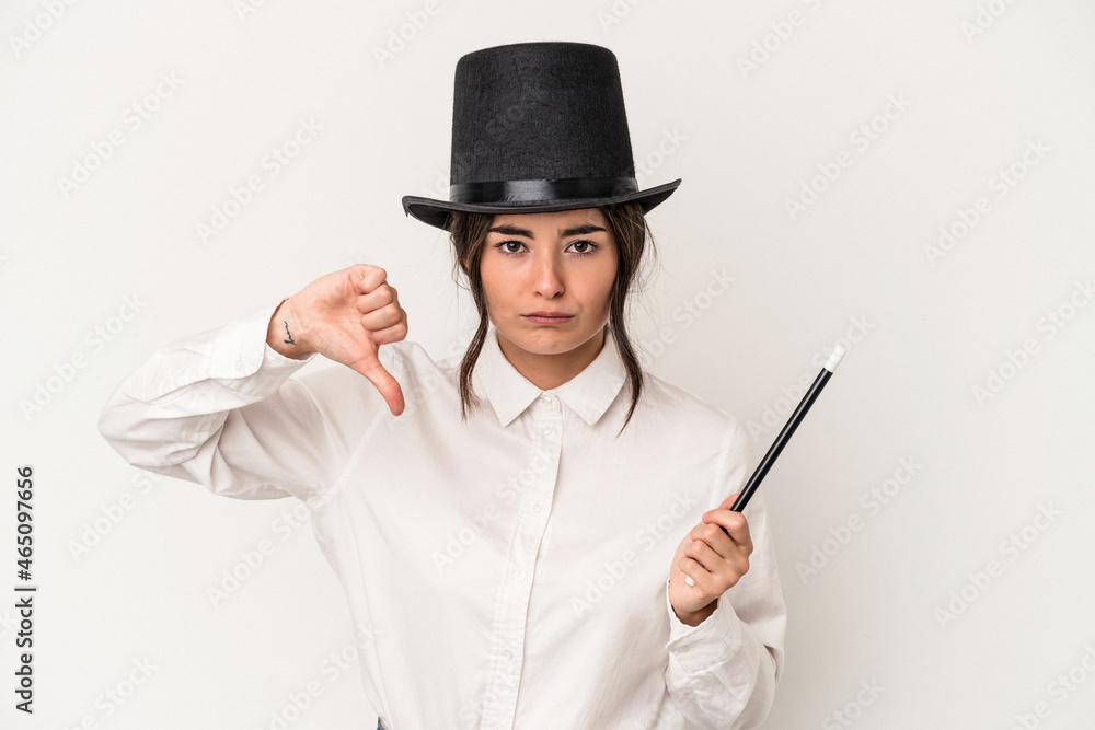 Young magician woman holding a wand isolated on white background showing a dislike gesture, thumbs down. Disagreement concept.
