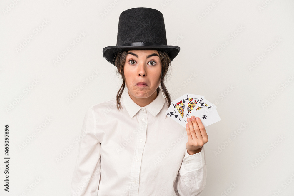 Young magician woman holding a wand isolated on white background shrugs shoulders and open eyes confused. Young magician woman holding a wand isolated on white background shrugs shoulders and open eyes confused.