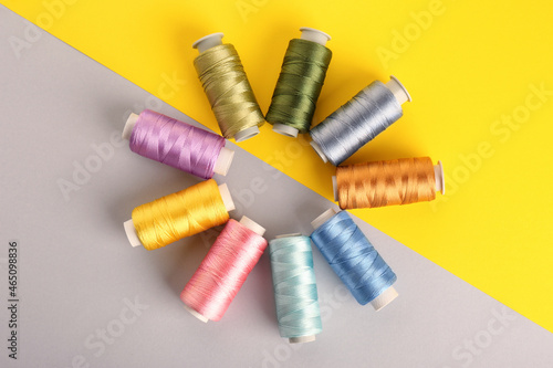 Different sewing threads on color background, flat lay