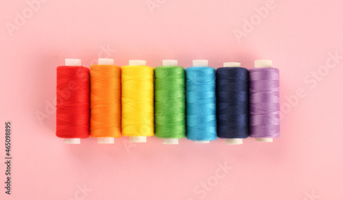 Different sewing threads on pink background, flat lay