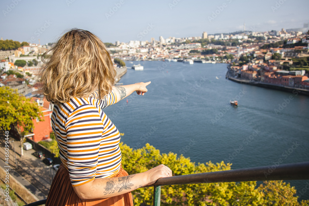 tourist in Porto, Portugal, at viewpoint crystal palace gardens pointing at city at douro river in Porto Portugal tourist exploring the city during summer and feeling happy and excited
