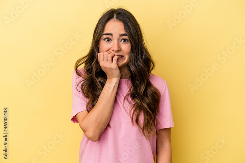 Young caucasian woman isolated on yellow background biting fingernails, nervous and very anxious.