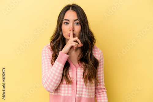 Young caucasian woman isolated on yellow background keeping a secret or asking for silence.