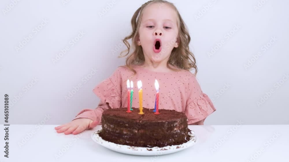 A cute little girl blows out candles on a birthday cake. Slow motion video. A cute little girl blows out candles on a birthday cake. Slow motion video.