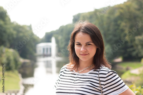Beautiful young girl with long hair and a striped T-shirt on the background of the park