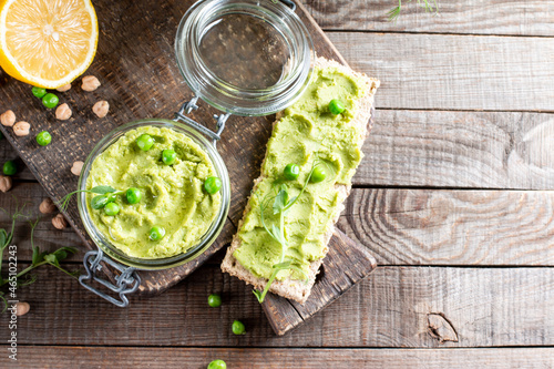 Hummus. Glass jar of homemade hummus garnished with chickpeas and green peas, olive oil. Flat lay, middle east food, vegetarian snack. Copy space