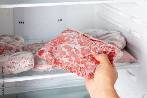 Man taking out frozen meat from freezer. photo