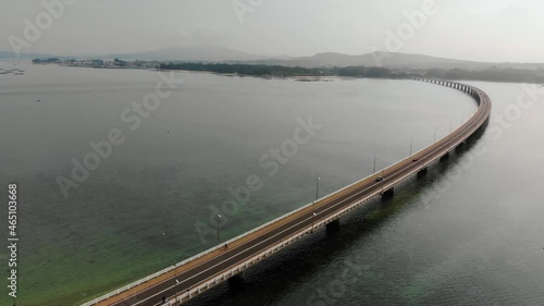 Aerial drone shot of the road linking the bay to an island. turquoise waters in the ocean and cars going through the bridge. beach
