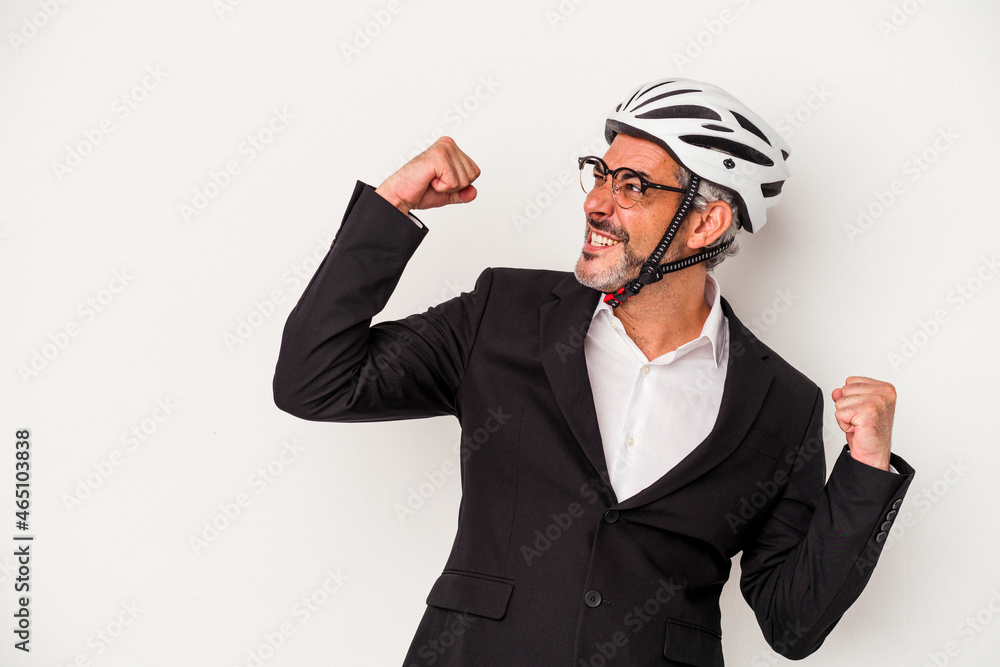 Middle age business man wearing a bike helmet isolated on blue background raising fist after a victory, winner concept. Middle age business man wearing a bike helmet isolated on blue background raising fist after a victory, winner concept.