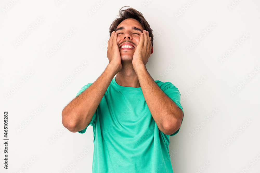 Young mixed race man isolated on white background laughs joyfully keeping hands on head. Happiness concept.