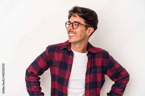 Young mixed race man isolated on white background laughs happily and has fun keeping hands on stomach.