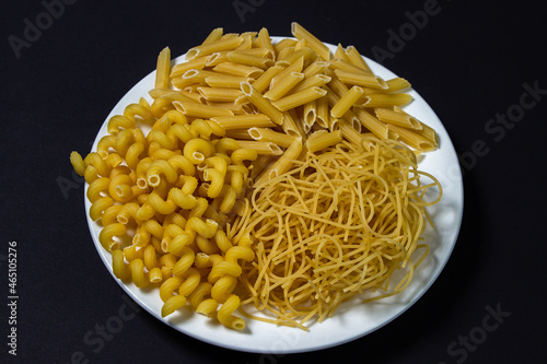 Raw pasta on a black background. Different varieties of pasta. Italian cuisine concept