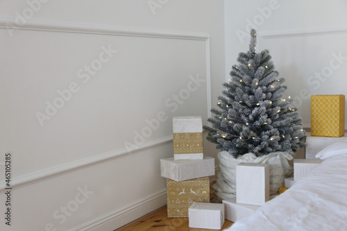 Elegant Christmas tree with white toys and gift boxes in the bedroom of luxury apartments
