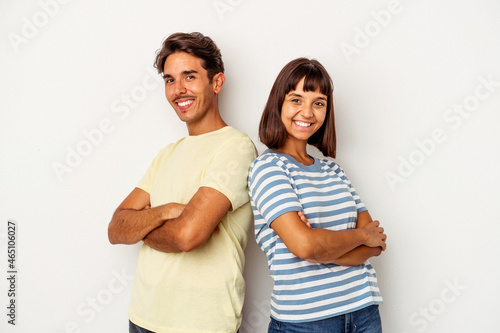 Young mixed race couple isolated on white background who feels confident, crossing arms with determination.