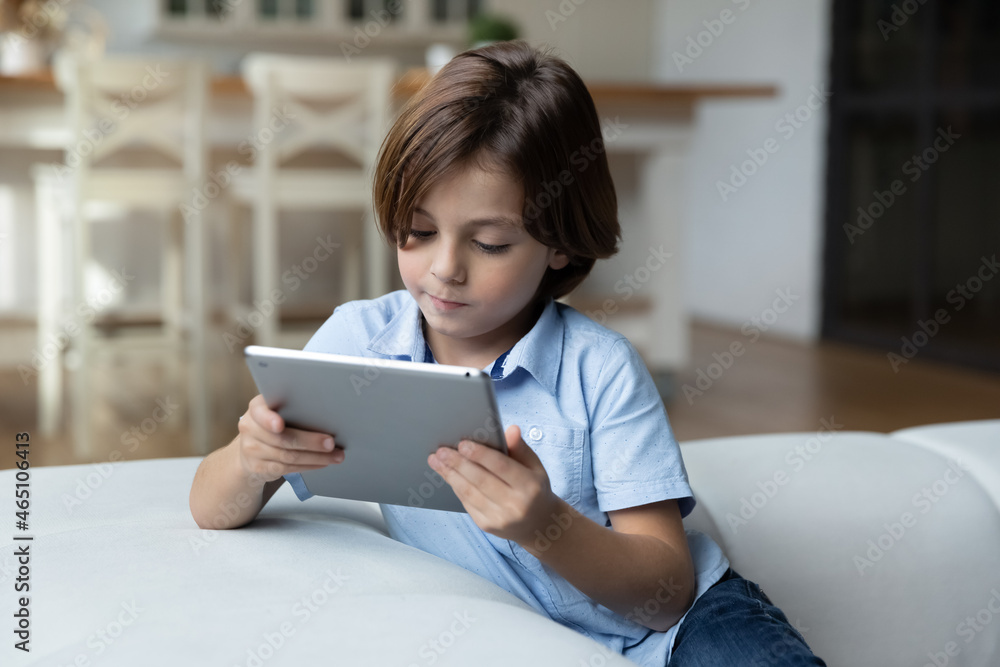 Concentrated serious gen Z school kid playing video game on tablet computer at home, using digital device, browsing internet, watching movie, media content, studying online, watching virtual lesson Concentrated serious gen Z school kid playing video game on tablet computer at home, using digital device, browsing internet, watching movie, media content, studying online, watching virtual lesson