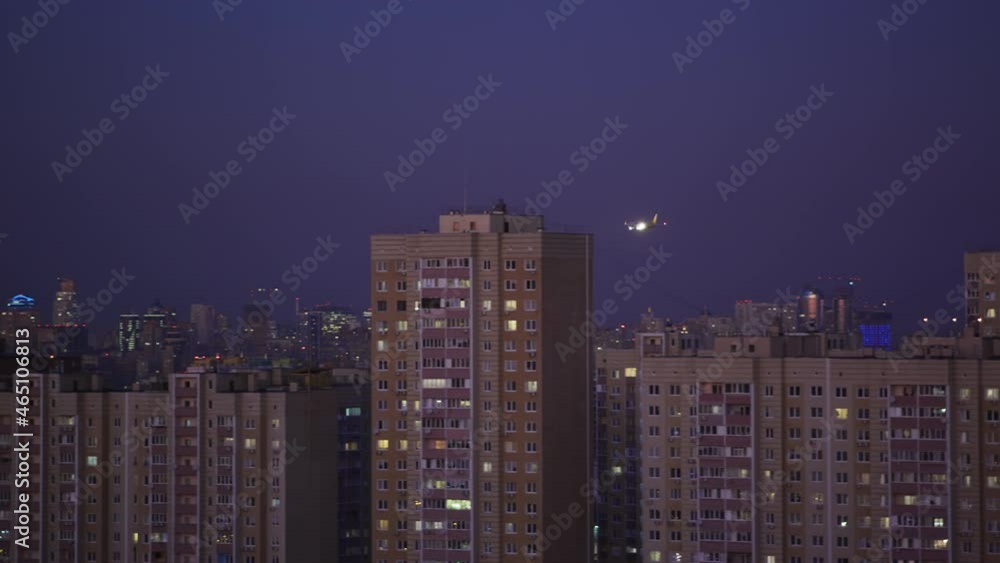 Passenger airplane flying on a low altitude over a city suburb while approaching airport on dusk Passenger airplane flying on a low altitude over a city suburb while approaching airport on dusk