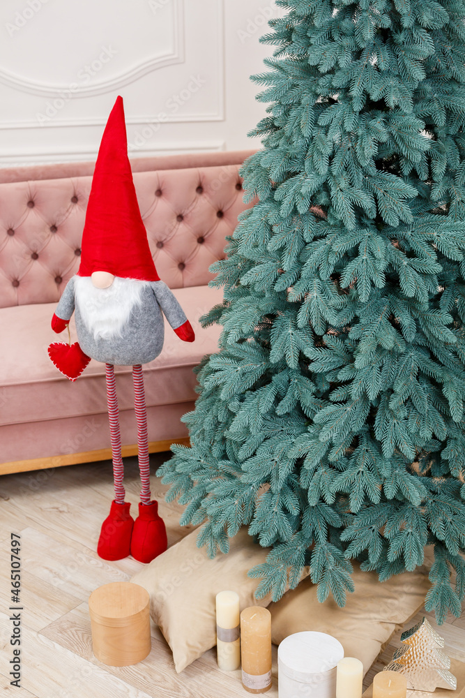 Obraz premium Christmas tree close-up without toys. Red toy elf gnome near the Christmas tree. Good New Year spirit.