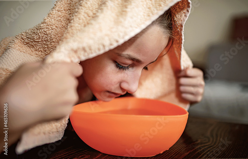 Bilde på lerret Little girl making inhalation with steamed aromatic water from the bowl