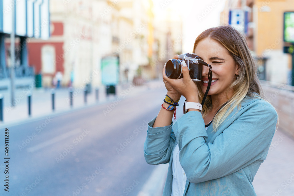 Smiling woman taking photo on camera in city