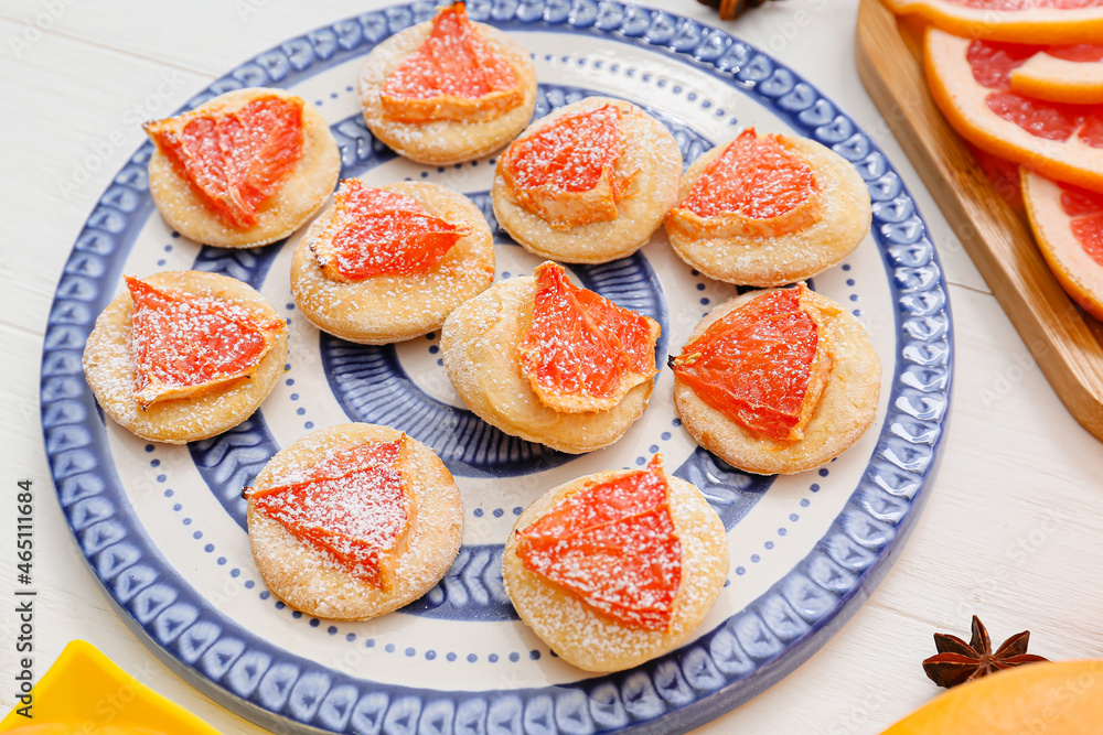 Plate with tasty grapefruit cookies on light wooden background, closeup Plate with tasty grapefruit cookies on light wooden background, closeup