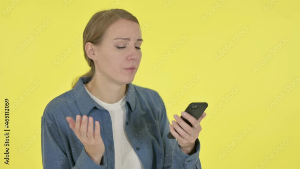Young Woman Loss on Smartphone on Yellow Background Young Woman Loss on Smartphone on Yellow Background