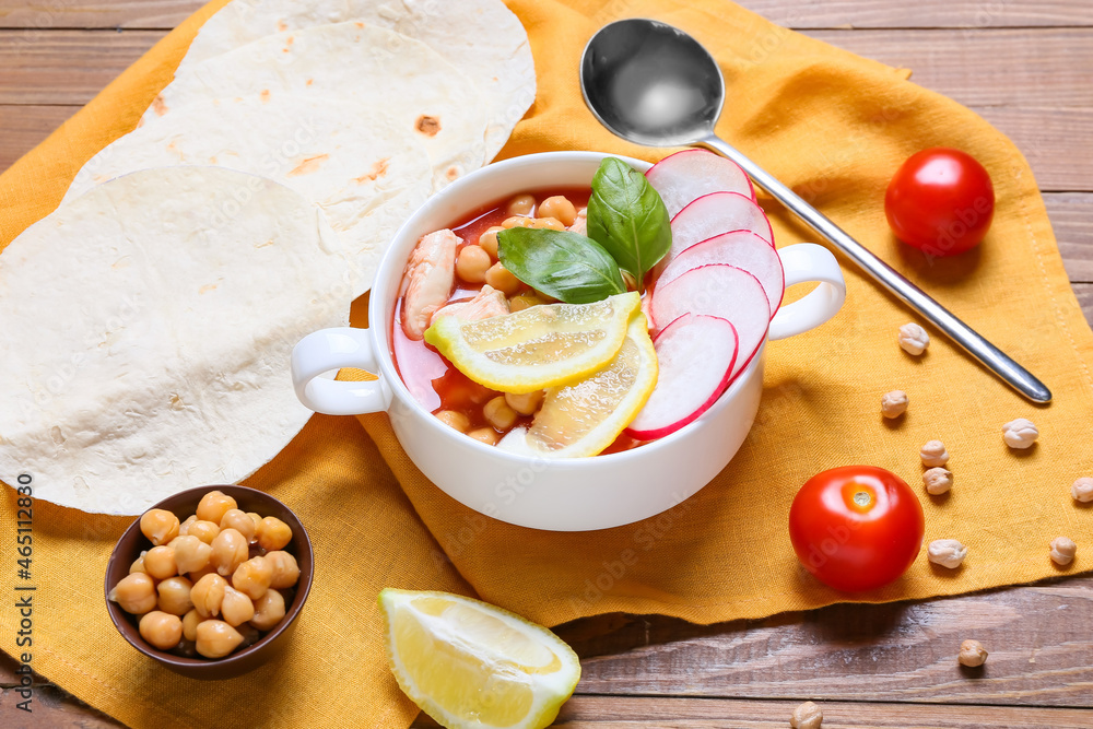 Bowl with delicious pozole soup and ingredients on wooden background