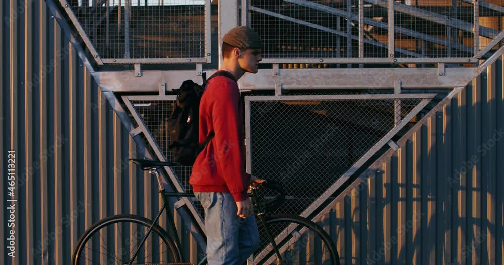 A young man leads a bicycle in his hands, steering around the city A young man leads a bicycle in his hands, steering around the city