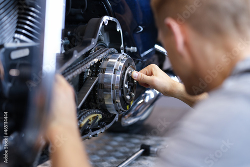 Mechanic repairs motorcycle engine in workshop closeup © H_Ko