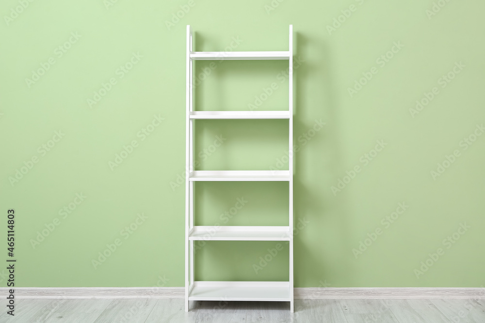 Stylish white shelf unit near color wall Stylish white shelf unit near color wall