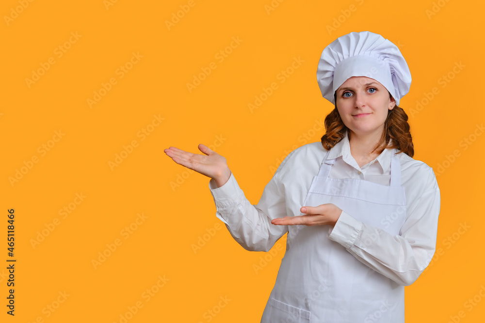 Happy woman chef on yellow studio background shows with hand on copy space for text Happy woman chef on yellow studio background shows with hand on copy space for text