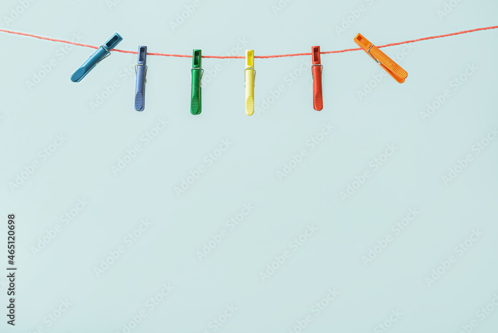Many plastic clothespins hanging on rope against blue background Many plastic clothespins hanging on rope against blue background