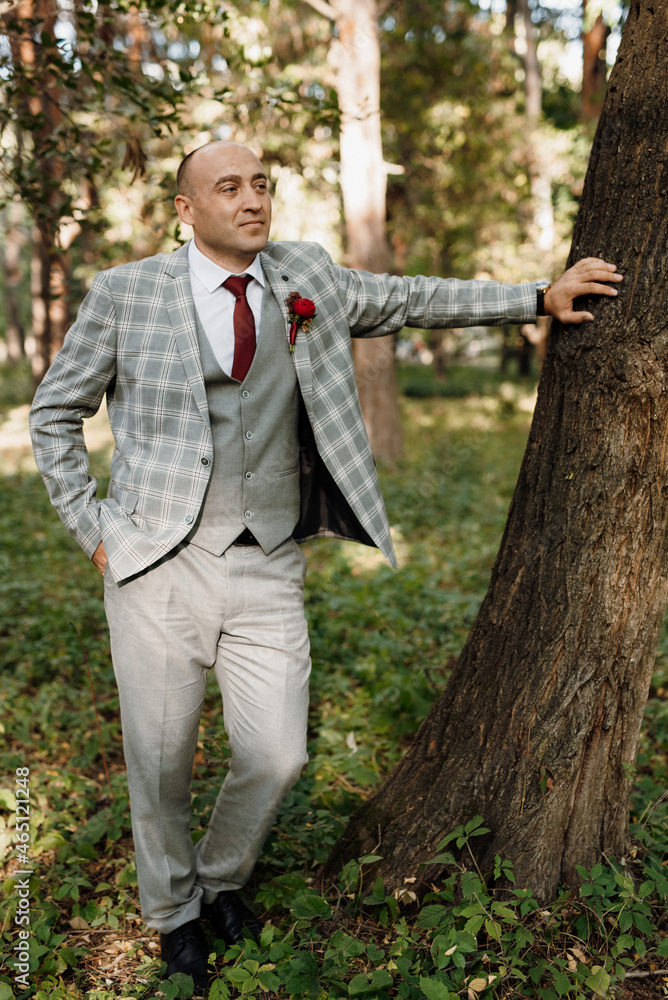 bald guy in a gray jacket on a background of tree bald guy in a gray jacket on a background of tree