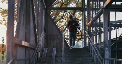 A man rides a bicycle to ladder, takes bicycle in his arms and carries it up