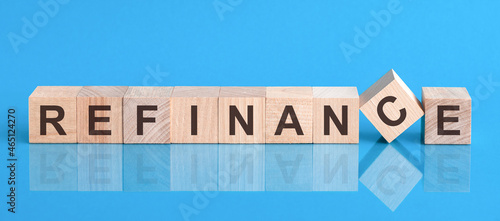 refinance word is made of wooden building blocks lying on the blue table, concept