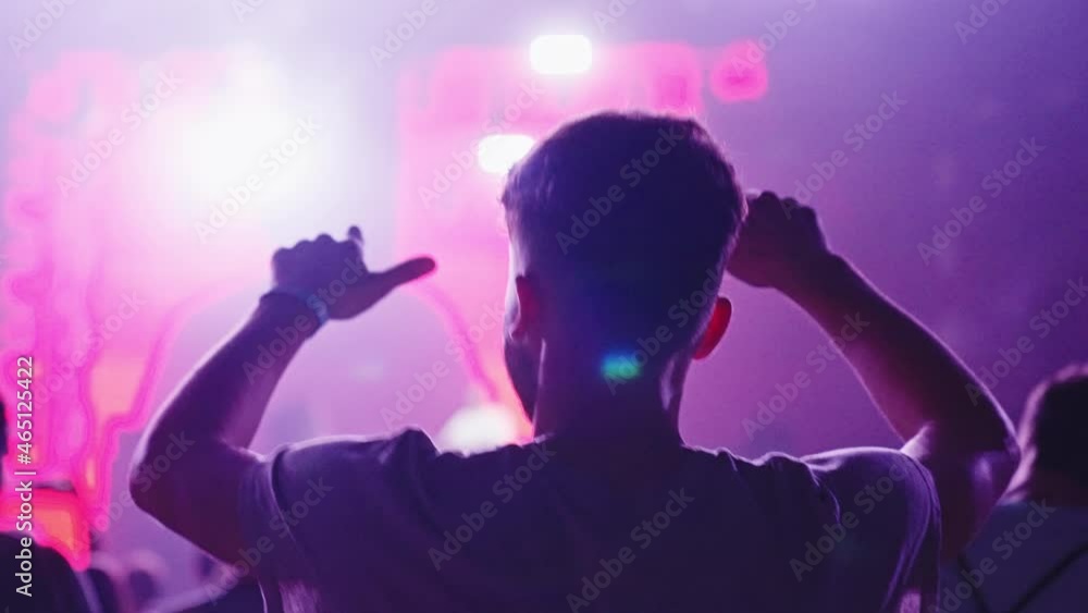 Crowd cheering on a music festival. Focus on a dancing man. Colorful illuminations and smoke Crowd cheering on a music festival. Focus on a dancing man. Colorful illuminations and smoke