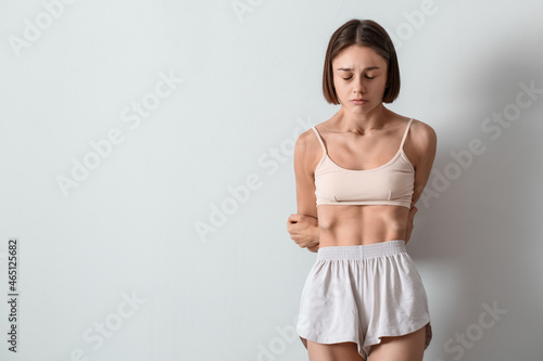 Photography Young skinny woman on light background. Anorexia concept