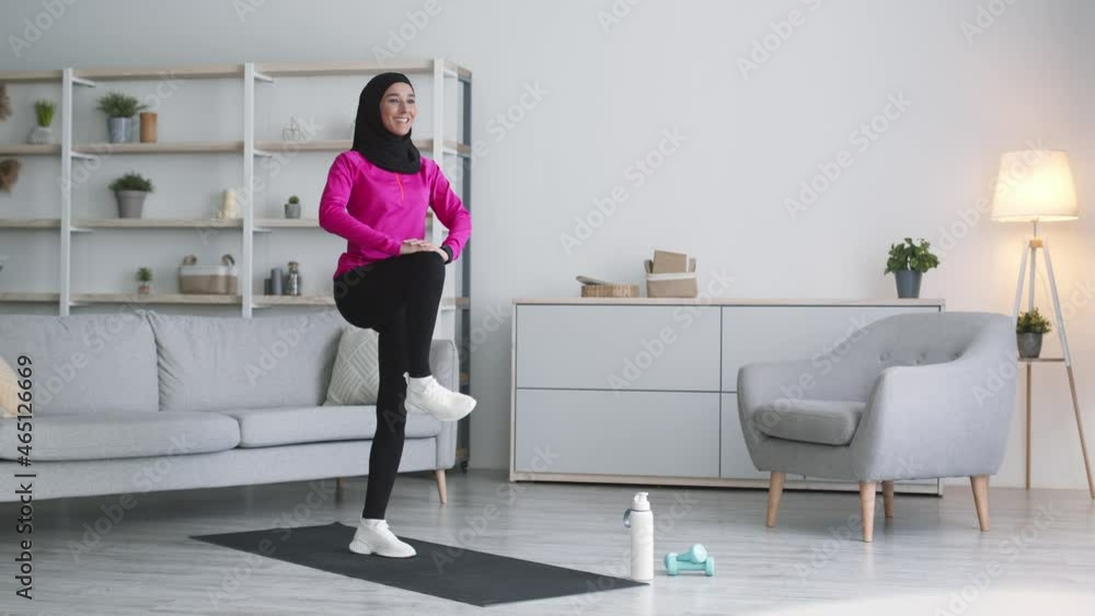 Sporty lifestyle and bodycare. Young middle eastern lady warming up her legs and feet at home, free space, slow motion Sporty lifestyle and bodycare. Young middle eastern lady warming up her legs and feet at home, free space, slow motion