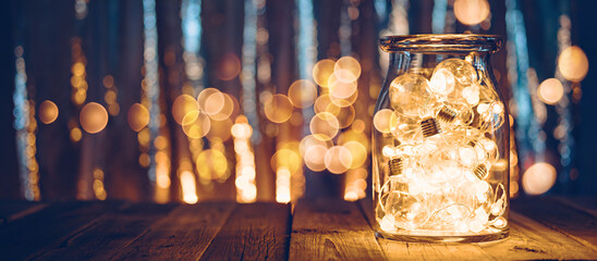 Large glass jar with light bulbs, Christmas lights and bokeh