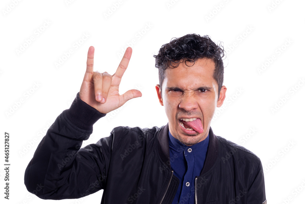 Man making rocker gesture, on white background. Young adult young man sticking out his tongue with rocker pose, hand with rock and roll sign. Man making rocker gesture, on white background. Young adult young man sticking out his tongue with rocker pose, hand with rock and roll sign.