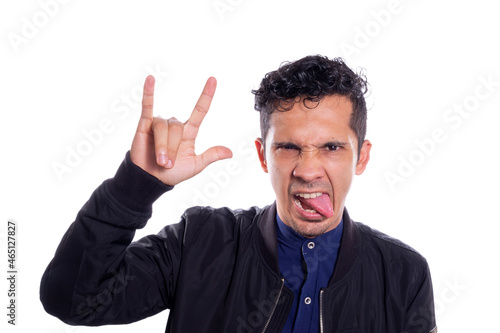 Man making rocker gesture, on white background. Young adult young man sticking out his tongue with rocker pose, hand with rock and roll sign.