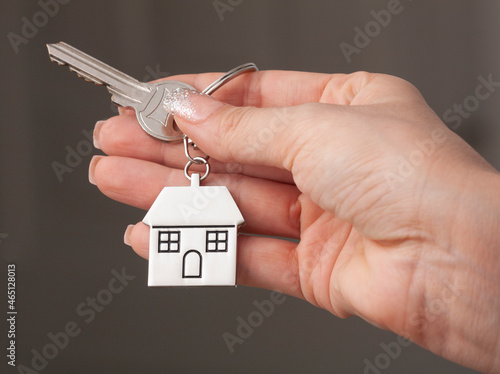 Holding house keys on house shaped keychain concept for buying a new home