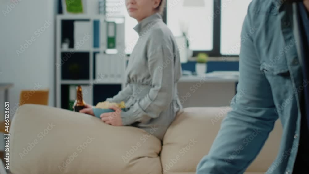 Portrait of woman with chips and bottle of beer after work, watching coworkers play game on foosball table. Person enjoying drinks and snacks to celebrate with fun activity after hours Portrait of woman with chips and bottle of beer after work, watching coworkers play game on foosball table. Person enjoying drinks and snacks to celebrate with fun activity after hours