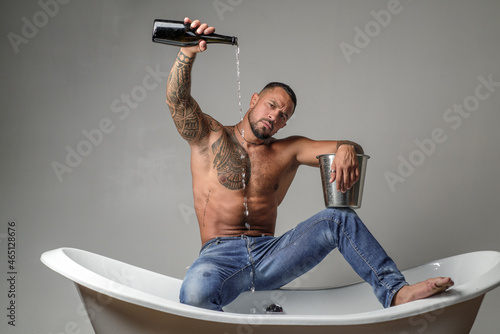Sexy man sit on bathtub in bathroom, men holiday with champagne. Celebrating christmas or birthday. Private sex party.