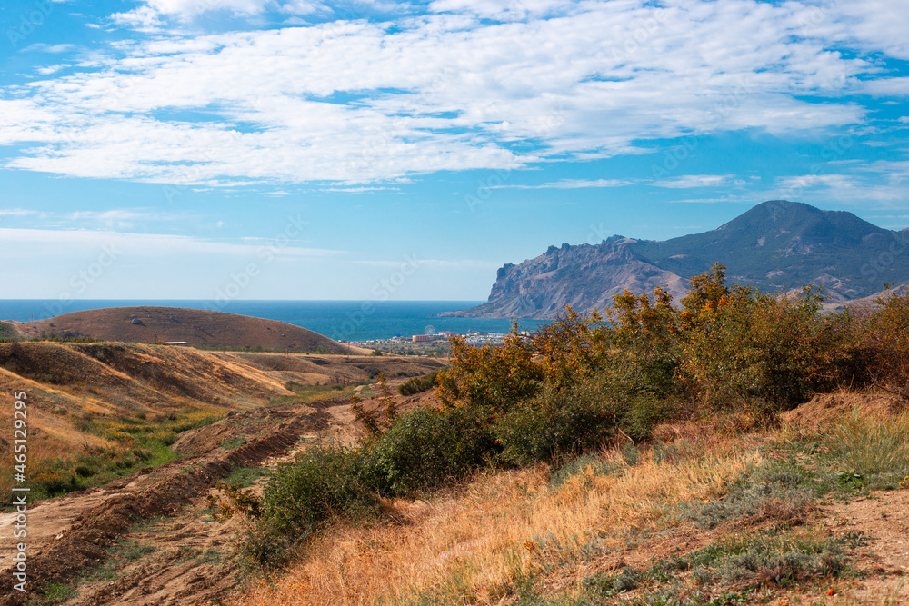 Autumn landscape. Mountain peaks and the sea with the resort village of Koktebel on a sunny day Autumn landscape. Mountain peaks and the sea with the resort village of Koktebel on a sunny day