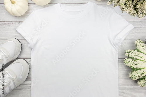 White womens cotton t-shirt mockup with pumpkins and sneaker on white wooden background. Design t shirt template, print presentation mock up. Top view flat lay.