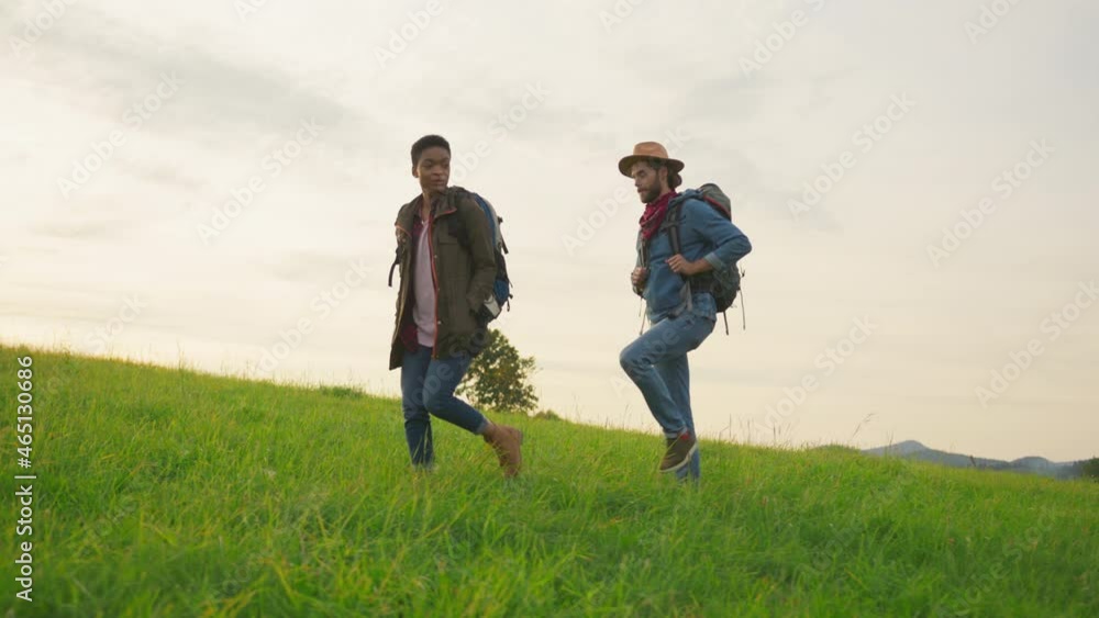 Multi-ethnic attractive young couple on high hills walking, exploring nature countryside and enjoying each other company. Hiking friends. Adventure tourism. Multi-ethnic attractive young couple on high hills walking, exploring nature countryside and enjoying each other company. Hiking friends. Adventure tourism.