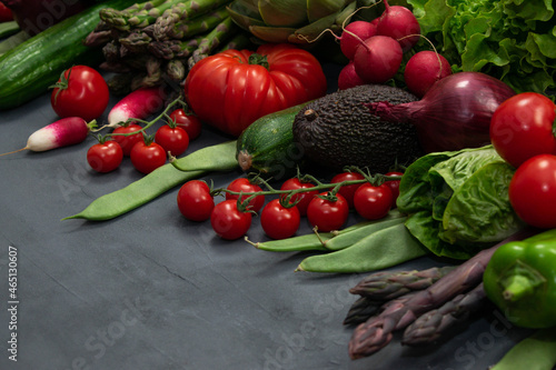 Different organic vegetables - asparagus  tomatoes cherry  avocado  artichoke  pepper  lime  redish  cauliflowerm  green beans  cucumber on gray background.