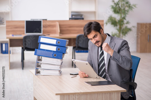 Young male employee unhappy with excessive work in the office