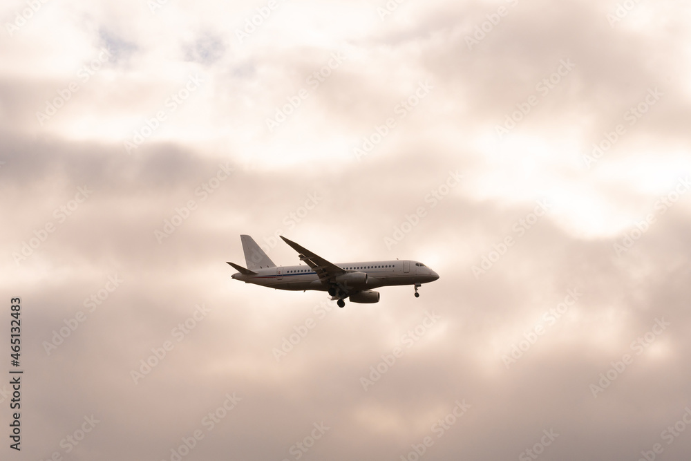 A passenger plane with a light beacon at the bottom of the fuselage on the background of cloudy sky on a cloudy day