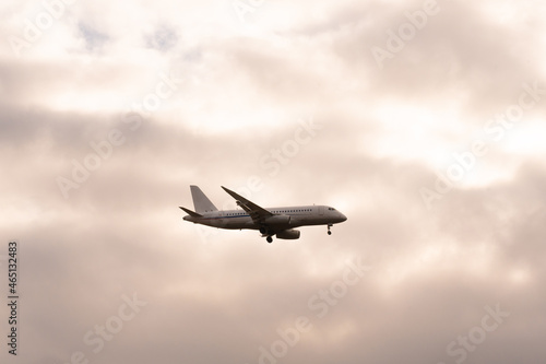 A passenger plane with a light beacon at the bottom of the fuselage on the background of cloudy sky on a cloudy day